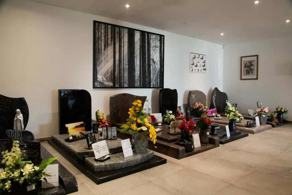 Salle d'exposition intérieure de stèles et monuments funéraires décorés de fleurs