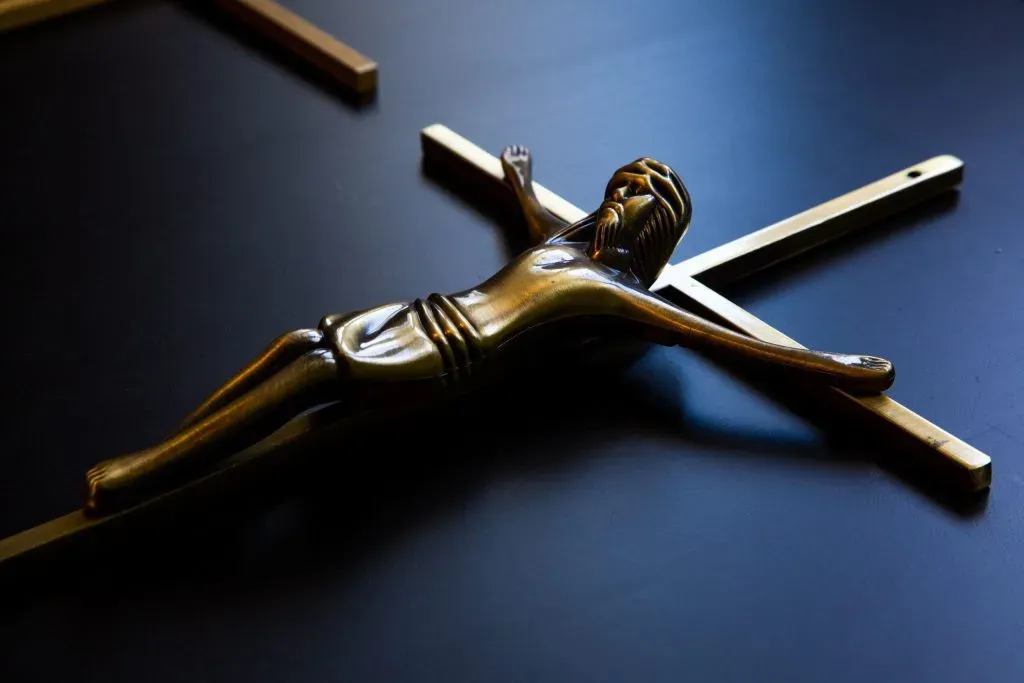Christ en bronze sur une croix funéraire posée sur une surface sombre