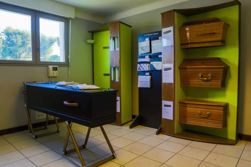 Salle d'exposition présentant des cercueils et modèles d'aménagements intérieurs de capitons