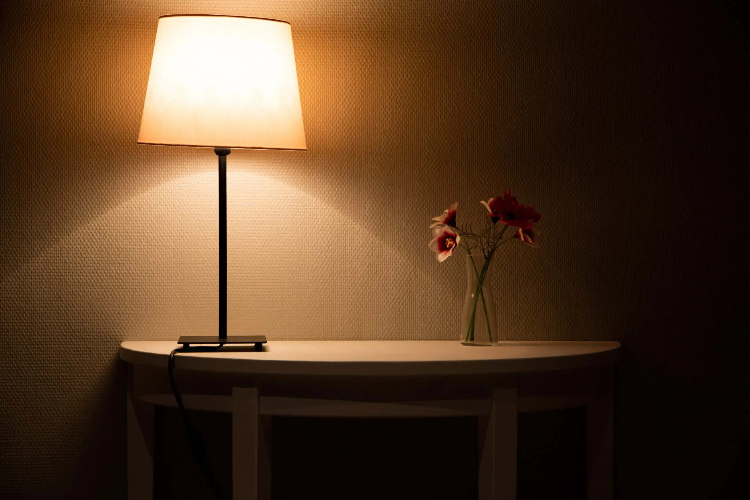 Lampe de table allumée éclairant un petit vase de fleurs dans un espace tamisé